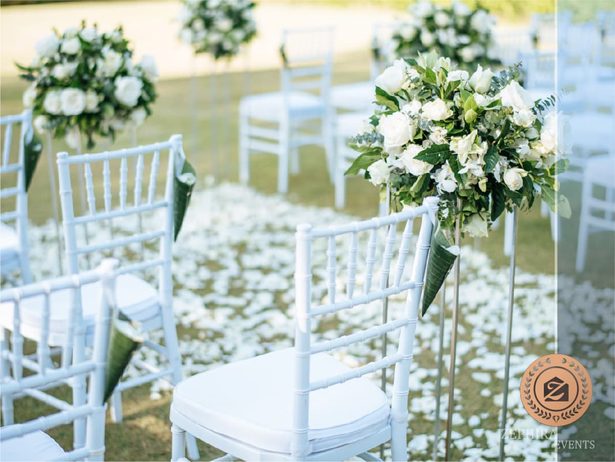 Scaune albe și aranjamente florale pe gazon