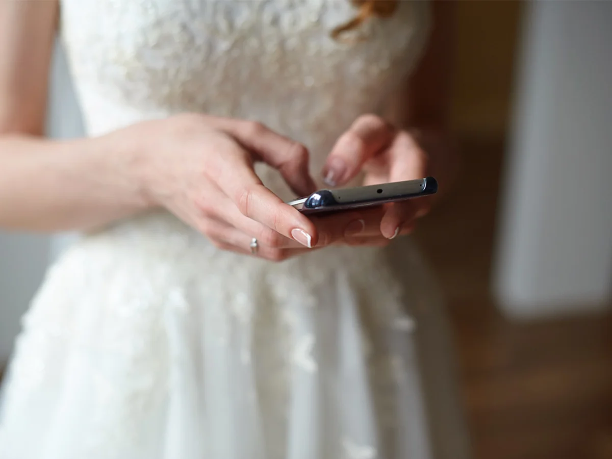 Mireasă trimițând un mesaj invitaților de pe telefon